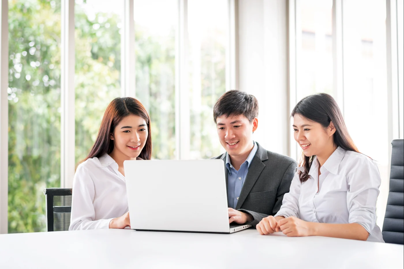 Three people collaborating around a laptop